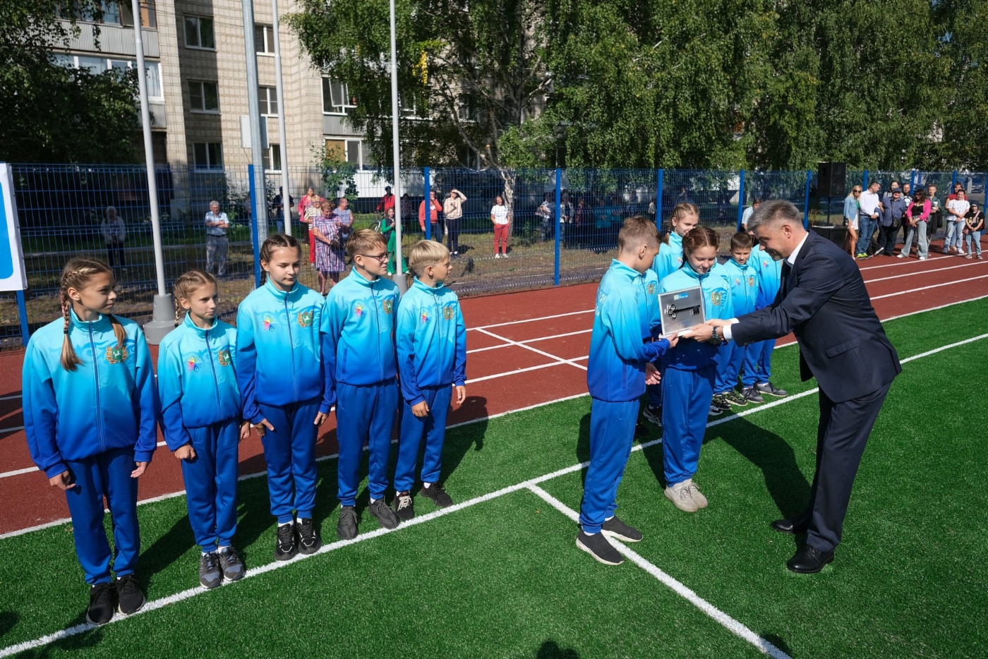 Генеральный директор Фонда поддержки социальных инициатив Газпрома Владимир Приймак вручает символический ключ от нового стадиона юным лицеистам